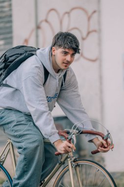 Sırt çantalı genç adam ya da öğrenci klasik bisiklete biniyor.