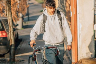 Sokakta klasik bir bisikletle yürüyen bir öğrenci.