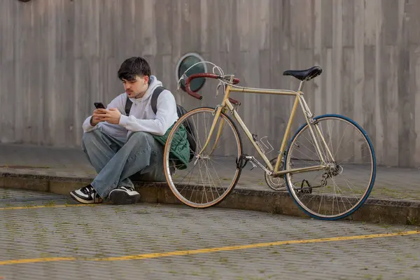 Cep telefonu ve klasik bisikleti olan genç bir adamın şehir manzarası
