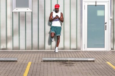 Yazın sokakta cep telefonuna bakan genç bir Afrikalı.