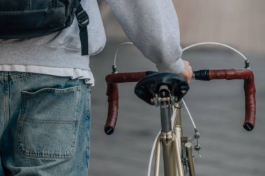 Sırt çantalı bisikletçi sokakta bisiklet taşıyor.