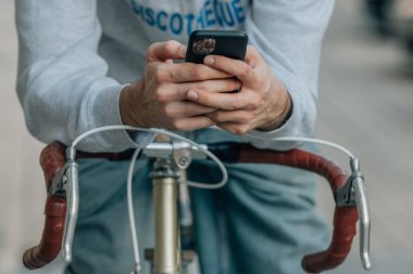 antika bisiklet üzerinde cep telefonu ya da akıllı telefon kullanan ellerin yakın plan görüntüsü