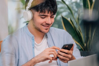 Kulaklık ve cep telefonu olan öğrenci ya da genç adam