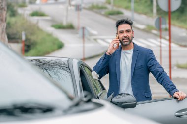 Genç bir adam ya da şoför arabadan çıkıp telefonuna ya da telefonuna bakıyor.