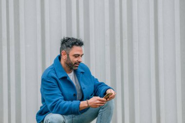 Mavi ceketli ve cep telefonlu genç adam.