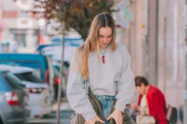 Kentsel kız sokakta ceketini giyiyor.