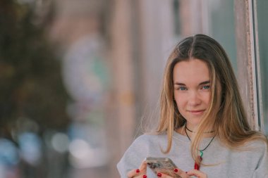 Sokakta cep telefonuyla dolaşan sarışın kız.