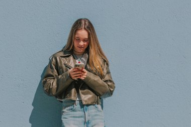 Sokakta cep telefonuyla dolaşan sarışın kız.