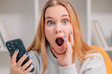 Genç sarışın kadın ya da mavi gözlü, cep telefonlu ve şaşkın bakışlı öğrenci.