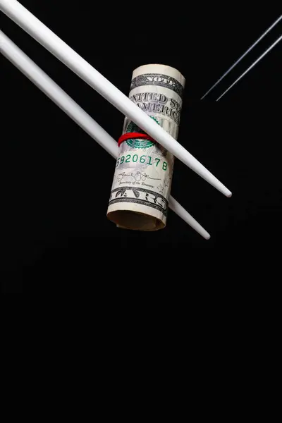 Chinese revenge. Wooden chopsticks hold an American dollar bill
