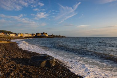 Evening tide on the beach in Aberystwyth at sunset. It is a seaside resort with a long promenade and is situated on the Welsh coast. clipart
