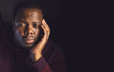 Genç Afrikalı Amerikalı evde üzgün ve depresif görünüyor.