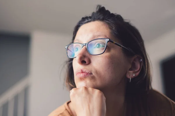 stock image Young millennial mother at home wearing prescription glasses looking of into distance sad and depressed.