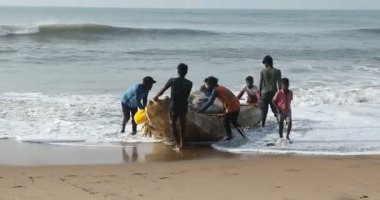 Kakinada Andhra Pradesh 'in 22 Şubat 2025' te denizden tekneyi çıkaran bir grup balıkçı.