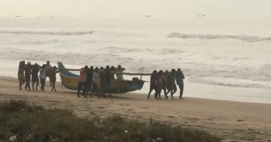 Kakinada Andhra Pradesh 'in 22 Şubat 2025' te denizden tekneyi çıkaran bir grup balıkçı.