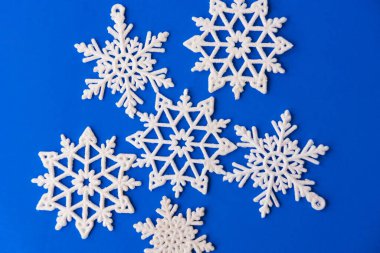 Mavi kağıt üzerinde beyaz kar taneleri süsü. Kar taneli klasik Noel kartpostalı. Güzel noel yıldızları mavi arka planda