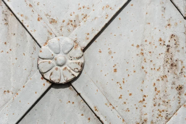 Round iron decoration on the metal door of christian church or cathedral. Detail of door with traditional floral ornaments. Old metal gray rust door with forged bars. Copy space and space for text