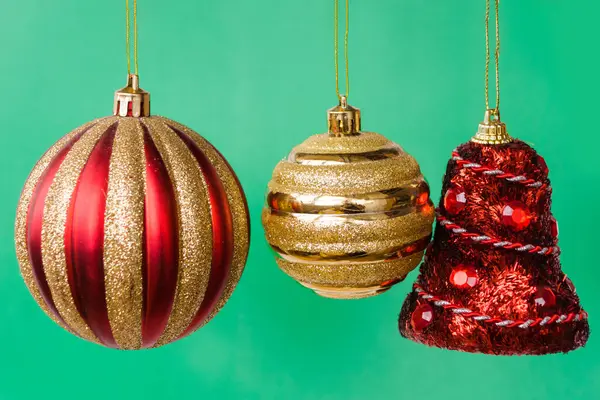 Три Рождественских Украшения Зеленом Фоне Красный Колокол Золотой Шар Серебряный — стоковое фото