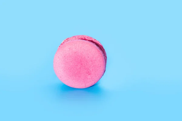Pembe Fransız kurabiyesi ya da mavi arka planda badem kurabiyesi. Lezzetli renkli badem kurabiyeleri. Kurabiye iki pürüzsüz yarıdan yapılmış, ince dolgularla bağlanmış. Yumurta beyazından yapılmış Fransız pastası..