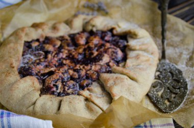 Siyah ahşap masanın üstünde erik meyveli turta crostata keten kumaş ve antika gümüş çatal bıçaklı pasta spatula yemek fotoğrafçılığı.