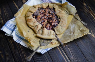 Ahşap masa üzerinde keten kumaşlı erik meyveli crostata turtası. Antika gümüş çatal bıçaklı pasta spatulası ve çatal yemek fotoğrafçılığıyla süslenmiş.