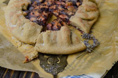 Siyah ahşap masanın üstünde erik meyveli turta crostata keten kumaş ve antika gümüş çatal bıçaklı pasta spatula yemek fotoğrafçılığı.
