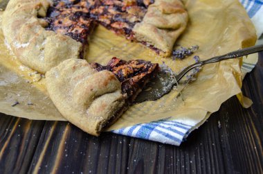 Siyah ahşap masanın üstünde erik meyveli turta crostata keten kumaş ve antika gümüş çatal bıçaklı pasta spatula yemek fotoğrafçılığı.