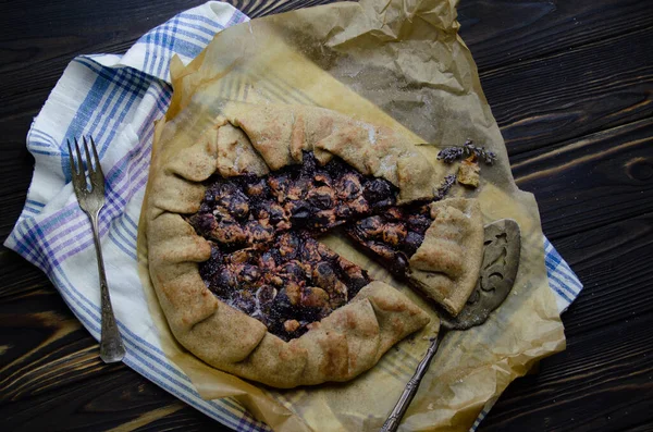 Siyah ahşap masanın üstünde erik meyveli turta crostata keten kumaş ve antika gümüş çatal bıçaklı pasta spatula yemek fotoğrafçılığı.