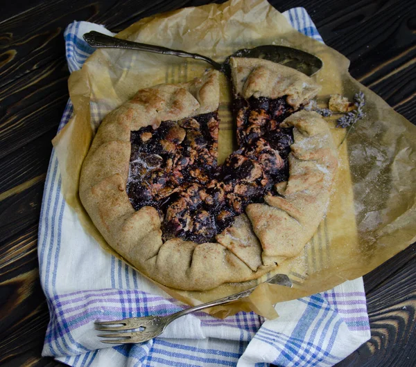 Siyah ahşap masanın üstünde erik meyveli turta crostata keten kumaş ve antika gümüş çatal bıçaklı pasta spatula yemek fotoğrafçılığı.