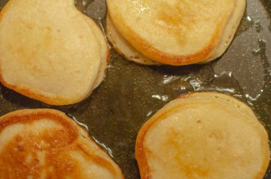 Mini küçük tereyağlı krepler, siyah tavada yağda kızartılmış oladi. Yaklaş.