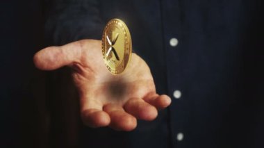 XRP şifreli dalgalanma 3 boyutlu bozuk para elinin üzerinde dönüyor. Elinde sembolü olan bir iş adamı. İş ve teknoloji kusursuz ve soyut kavramlarla donatılmış.