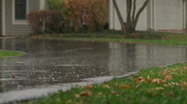 Slow Motion, heavy rain water drops falling into big puddle on asphalt, flooding the street. High quality 4k footage
