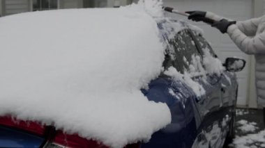 Kar yağdıktan sonra mavi arabayı temizleyen kadın. Yüksek kalite 4k görüntü
