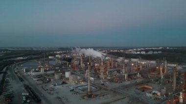 Alacakaranlıkta petrol rafinerisi petrokimya fabrikasıyla birlikte petrol ve gaz yakıtlı kimyasal tankın havadan çekimi. Yüksek kalite 4k görüntü