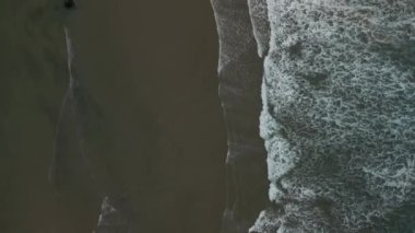 Okyanus dalgası yuvarlanmasının yukarıdan aşağıya havadan çekilmiş görüntüsü düz bir çizgide sahile çarpıyor, kumlu kumsalda. - Evet. Yüksek kalite 4k görüntü