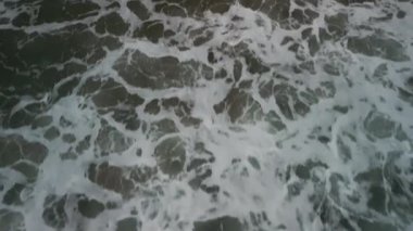 Okyanus dalgası yuvarlanmasının yukarıdan aşağıya havadan çekilmiş görüntüsü düz bir çizgide sahile çarpıyor, kumlu kumsalda. - Evet. Yüksek kalite 4k görüntü