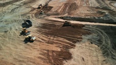 Yukarıdan aşağıya doğru geniş çekim. Bir buldozer, gelişim için bir arazi alanı oluşturur. Yüksek kalite 4k görüntü