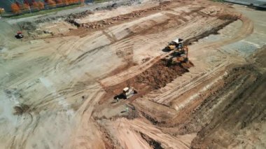 Yukarıdan aşağıya doğru geniş çekim. Bir buldozer, gelişim için bir arazi alanı oluşturur. Yüksek kalite 4k görüntü