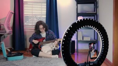 Sanat Kadını Blog yazarları, Online Ders Kayıt, Gitar Çalma. Cep telefonu kullanırken gitar çalan neşeli kadın blogcu. Yüksek kalite 4k görüntü