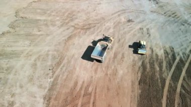 Yukarıdan aşağıya doğru geniş çekim. Bir buldozer, gelişim için bir arazi alanı oluşturur. Yüksek kalite 4k görüntü