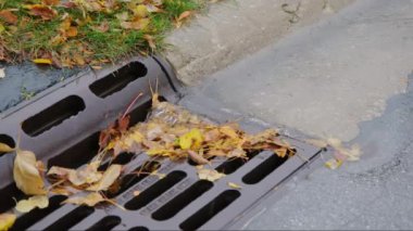 Yağmur suyunun yukarıdan aşağıya enkazlı görüntüsü sokağın kenarındaki rögardan aşağı akıyor. Yüksek kalite 4k görüntü