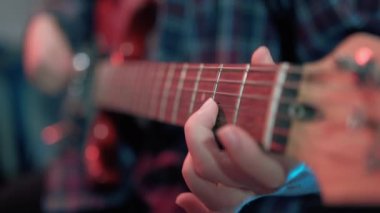 Neşeli genç kızın otururken gitar çalarkenki yakın çekimi. Yüksek kalite 4k görüntü
