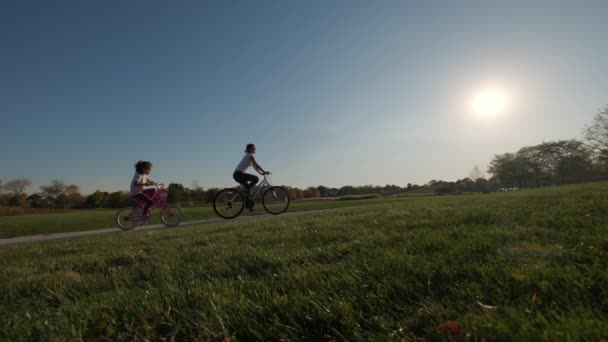 阳光明媚的日子里 母亲和女儿在公园和郊区的街上骑自行车 高质量的4K镜头 — 图库视频影像