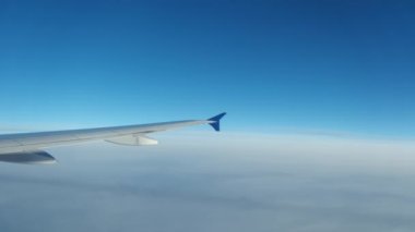 Bulutların üzerinde uçan kanat, yolcu tarafından lomboz deliğinden görüldüğü gibi. Geniş açı. Yüksek kalite 4k görüntü