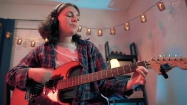 Neşeli genç kızın otururken gitar çalarkenki yakın çekimi. Yüksek kalite 4k görüntü