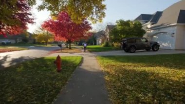 Anne ve kızı güneşli bir günde bir parkta ve banliyö caddesinde bisiklet sürerler. Yüksek kalite 4k görüntü