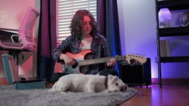 Bir köpekle otururken gitar çalan neşeli bir genç kadın. Yüksek kalite 4k görüntü