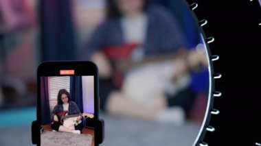 Sanat Kadını Blog yazarları, Online Ders Kayıt, Gitar Çalma. Cep telefonu kullanırken gitar çalan neşeli kadın blogcu. Yüksek kalite 4k görüntü