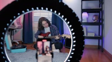 Sanat Kadını Blog yazarları, Online Ders Kayıt, Gitar Çalma. Cep telefonu kullanırken gitar çalan neşeli kadın blogcu. Yüksek kalite 4k görüntü