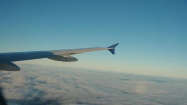 Bulutların üzerinde uçan kanat, yolcu tarafından lomboz deliğinden görüldüğü gibi. Geniş açı. Yüksek kalite 4k görüntü